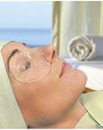 Person receiving facial treatment with transparent face masks in a spa setting.